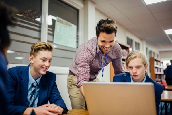 A group of young men sitting around a laptop.